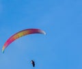 Orange and yellow paraglider on clear blue sky