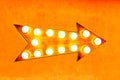 Orange, yellow and reddish color vintage bright and colorful illuminated metallic display arrow sign on orange wall