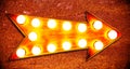 Orange, yellow and reddish color vintage bright and colorful illuminated metallic display golden arrow sign w/ glowing light bulbs