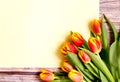 Orange and yellow tulip bouquet and blank greeting card. Top view over wooden table Royalty Free Stock Photo