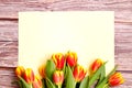 Orange and yellow tulip bouquet and blank greeting card. Top view over wooden table Royalty Free Stock Photo