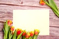 Orange and yellow tulip bouquet and blank greeting card. Top view over wooden table Royalty Free Stock Photo