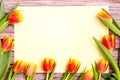 Orange and yellow tulip bouquet and blank greeting card. Top view over wooden table Royalty Free Stock Photo