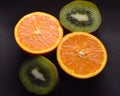 Oranges, kiwi, cut on a plate dark color