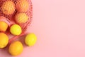 Oranges and lemons in reusable cotton net bag on pink background.