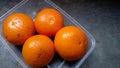 Oranges placed in plastic container on a cement bench. High angle view. Fresh fruit.