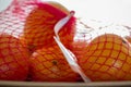 Oranges in plastic netting on a platter. Pile fresh oranges in plastic red mesh sack