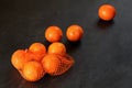 Oranges in red plastic net, some scattered on black stone like board Royalty Free Stock Photo