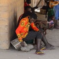 Unidentified local man in colored shirt sits and holds a knife