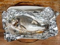 Orata fish baked in foil on old wooden table Royalty Free Stock Photo