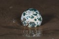 Orbicular Ocean Jasper sphere with crystallized vugs from Madagascar on wet sand in front of the lake at sunrise