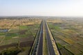 orbit aerial drone shot of new delhi mumbai jaipur express elevated highway showing six lane road with green feilds with