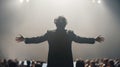 Orchestra conductor with open arms ready to lead, back to audience under spotlight. His silhouette is powerful presence