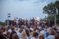 Orchestra performing live concert for audience under blue sky