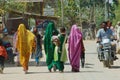 Indian women wearing colorful sarees walk by the street in Orchha, India.