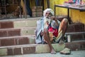 An elderly male Hindu pilgrim sitting on the street