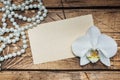 Orchid flower, beads and a form for text on a wooden table. Concept romance mood. Copy space and flat lay Royalty Free Stock Photo