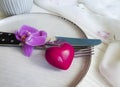 orchid flower plate, heart, fork knife on a wooden background