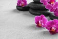 Orchid with spa stones on  grey background. Space for text Royalty Free Stock Photo