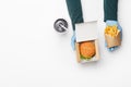 Order in fast food restaurant. Waiter in rubber gloves gives burger in cardboard box, and french fries in paper bag, and