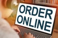 Order Online, text words typography written on laptop, over shoulder man buying on e-commercel Royalty Free Stock Photo
