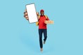 Order Pizza Online. Cheerful Black Delivery Guy Jumping And Showing Blank Smartphone Royalty Free Stock Photo