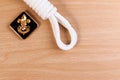 Orderliness white scout rope with vintage boy scouts badge on wooden table.