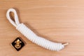 Orderliness white scout rope with vintage boy scouts badge on wooden table. Royalty Free Stock Photo