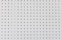 Orderly dot or holes rows and columns on white pegboard wall