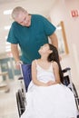 An Orderly Pushing A Little Girl In A Wheelchair