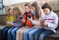 Ordinary children playing with the phone on bench outdoors Royalty Free Stock Photo