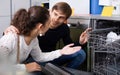 Ordinary couple choosing new dish washing machine in supermarke Royalty Free Stock Photo