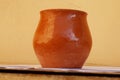 An ordinary simple clay pot of red and brown color with a glossy surface and glints of light. Small shallow cracks are Royalty Free Stock Photo