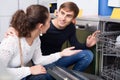 Ordinary young customers choosing new dish washing machine in supermarket Royalty Free Stock Photo