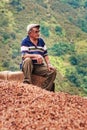 Senior worker sits behind heap of hazelnuts during hazelnut harvest in Ordu, Turkey