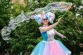 Orel, Russia, May 26, 2019: Twin Festival. Smiling woman in bright unicorn costume making big soap bubbles