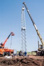 Construction site, workers using construction equipment install a wind turbine tower