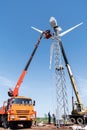 Construction of a wind power plant. Installers using a truck crane and aerial platform install a wind turbine rotor Royalty Free Stock Photo