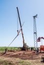 Construction workers using a truck crane lift the rotor of a wind turbine