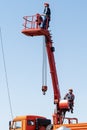 Worker in a basket of a telescopic aerial platform against a blue sky