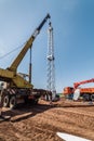 Workers using construction equipment install a wind generator