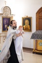 Orenburg, Russian Federation-2 Aprel 2019. Orthodox priest holding a baby during the baptism ritual