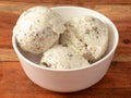 ice cream scoops served in a bowl over a rustic wooden table, selective focus