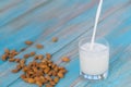 Organic almond milk is poured into a glass on blue wooden background Royalty Free Stock Photo