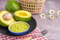 Organic avocado with seed, avocado halves, and fresh guacamole in a bowl on a black plate with cloth and cutlery on a gray stone Royalty Free Stock Photo