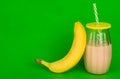 Organic banana drink and one banana on a bright green background.Copy space.