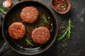 Organic beef hamburger patties with spices in a frying pan. Top view