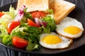 Organic breakfast of fried eggs with fresh salad and toast close Royalty Free Stock Photo