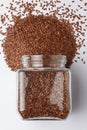 Organic Brown flaxseeds Linum usitatissimum or linseed, spilled and in a glass jar,