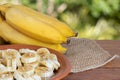 Organic bunch of ripe yellow bananas. Pieces cut on a plate with honey and oats. Isolated with blurred green background.Copy space Royalty Free Stock Photo